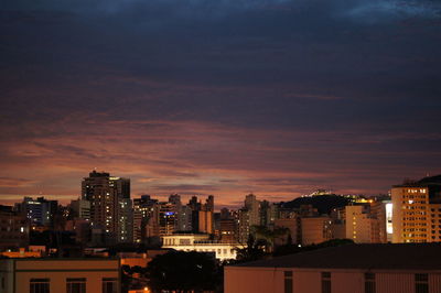 Illuminated cityscape against sky at sunset