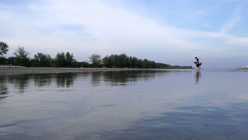 Man standing by lake against sky
