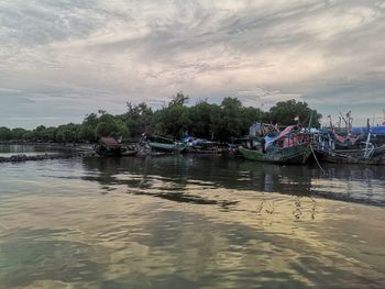 Boats moored in river against sky during sunset