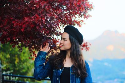 Portrait of beautiful young woman standing against trees during autumn