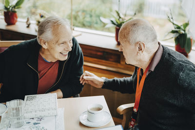 High angle view of senior men discussing while sitting at table in retirement home
