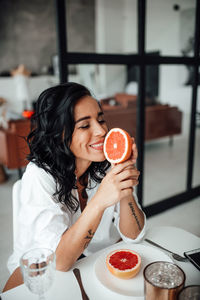 Smiling woman holding blood orange at kitchen