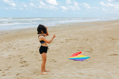 Rear view of woman with surfboard at beach against sky