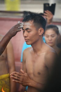 Cropped hand rubbing ash on man forehead