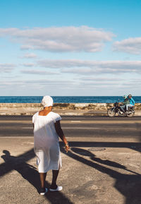 Rear view of man on beach against sky