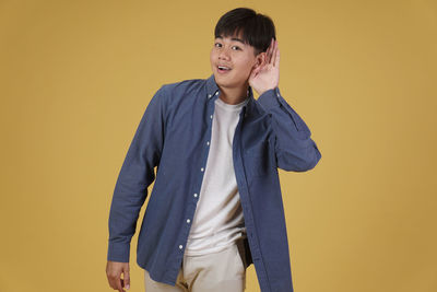 Portrait of a smiling young man against yellow background