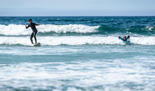 People surfing at sea against sky