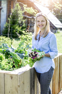 Portrait of mid adult woman holding radishes at farm