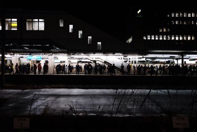 People waiting at railroad station platform at night