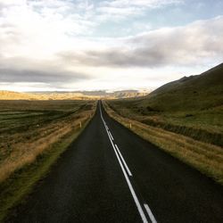 Empty road along landscape against sky