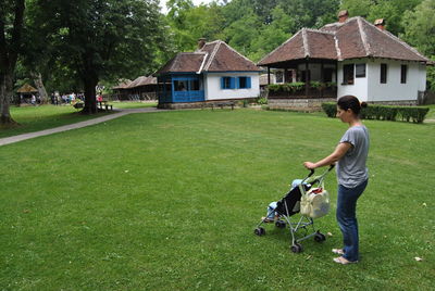 Mother with daughter in baby stroller standing at park