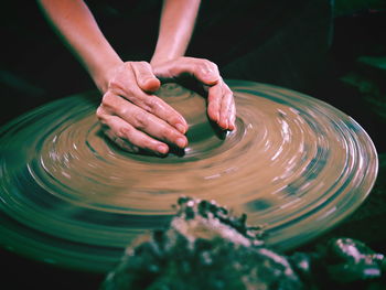 Cropped hands of potter shaping earthenware on pottery wheel