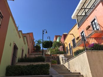 Street amidst buildings against clear blue sky