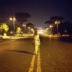 Woman standing on road at night