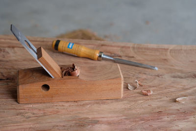 High angle view of plane by chisel on wooden plank at workshop