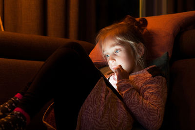 Portrait of girl using digital tablet on sofa