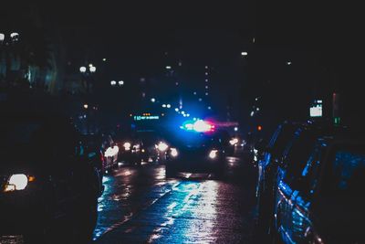 Cars on illuminated city street at night