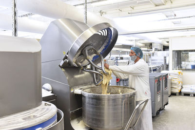 Worker operating dough kneading machine in an industrial bakery