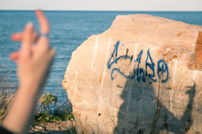 Shadow of hand on sea shore against sky