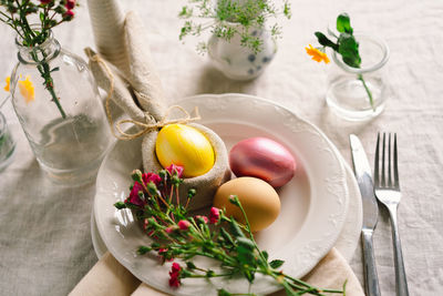 Happy easter. stylish easter eggs on a napkin with spring flowers on white wooden background