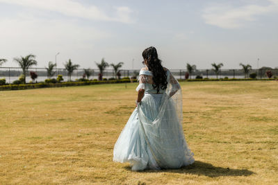 Full length of woman standing on field against sky