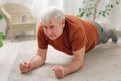 Happy smiling mature senior man doing exercises of gymnastics at home. concept of healthy lifestyle