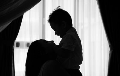 Silhouette man sitting by window at home