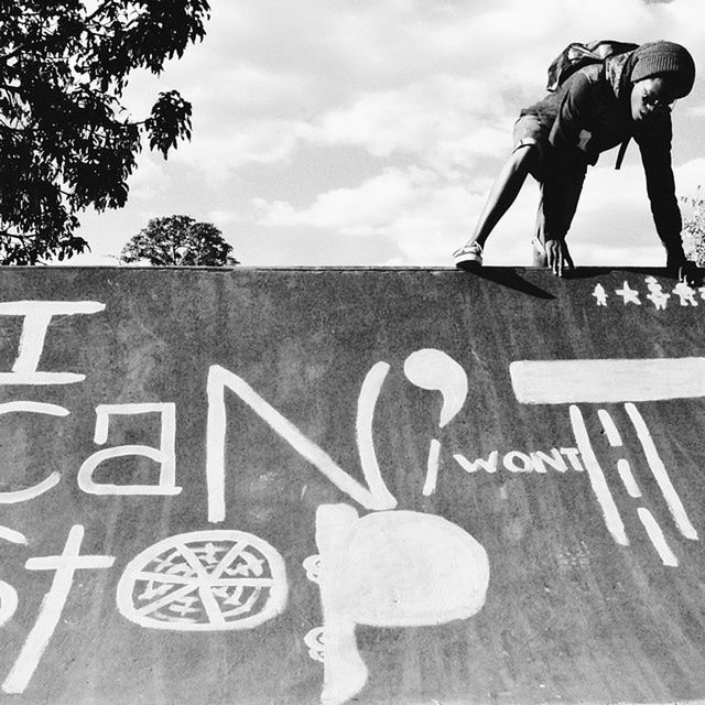 text, human representation, communication, western script, art and craft, art, sky, creativity, sign, bicycle, low angle view, men, lifestyles, graffiti, leisure activity, sculpture, road sign