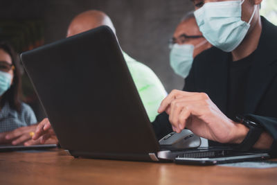 People wearing mask using laptop at office