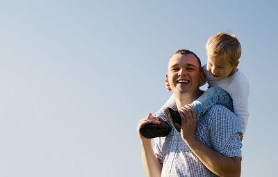 Cheerful father and son against sky