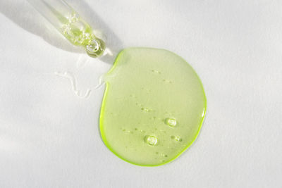 Pipette with green hyaluronic acid on white background. cosmetics, healthcare concept. dose of serum