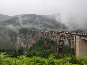 Arch bridge over mountains against sky