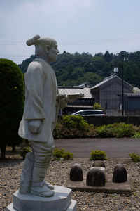 Statue against trees and building against sky