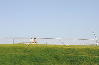 View of grassy field against clear sky