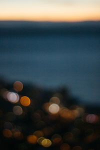 Defocused image of illuminated lights against sky at night