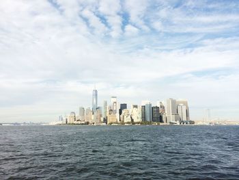 Sea by modern buildings against sky in city