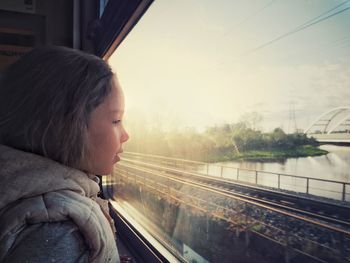 Profile view of girl looking through train window during sunset