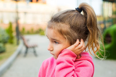 Close-up of cute girl looking away while standing outdoors