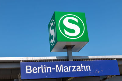 Low angle view of road sign against clear blue sky