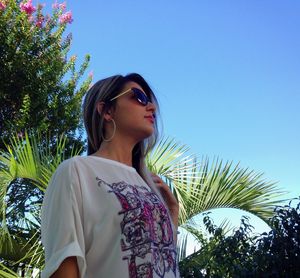 Low angle view of woman standing against blue sky