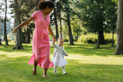 Girl and woman standing on grass against trees