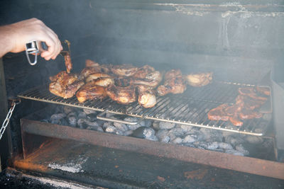 View of man preparing food on barbecue grill