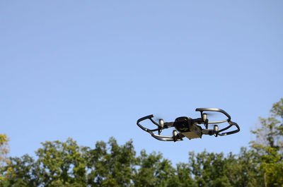 Low angle view of helicopter against clear blue sky