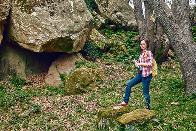 Woman exploring forest, walking through a grove, traveling with backpack or exercising outdoors. 