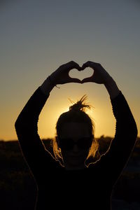 Silhouette person against sky at sunset