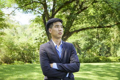 Portrait of young man standing against trees