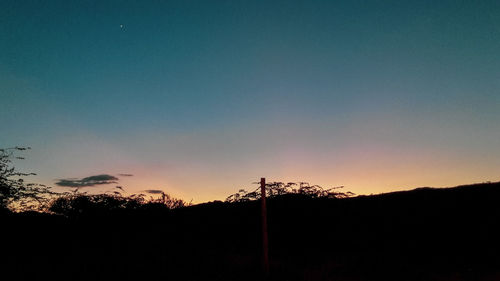 Silhouette trees on landscape against sky during sunset