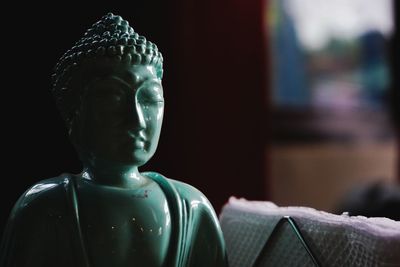 Close-up of buddha statue in darkroom