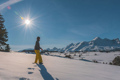 A full-body shot of a young caucasian woman walking towards the camera in the french alps mountains