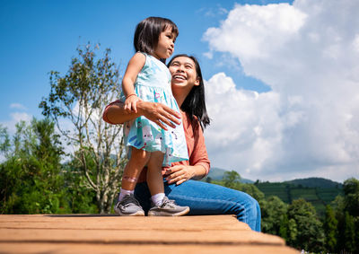 Smiling woman and daughter against sky
